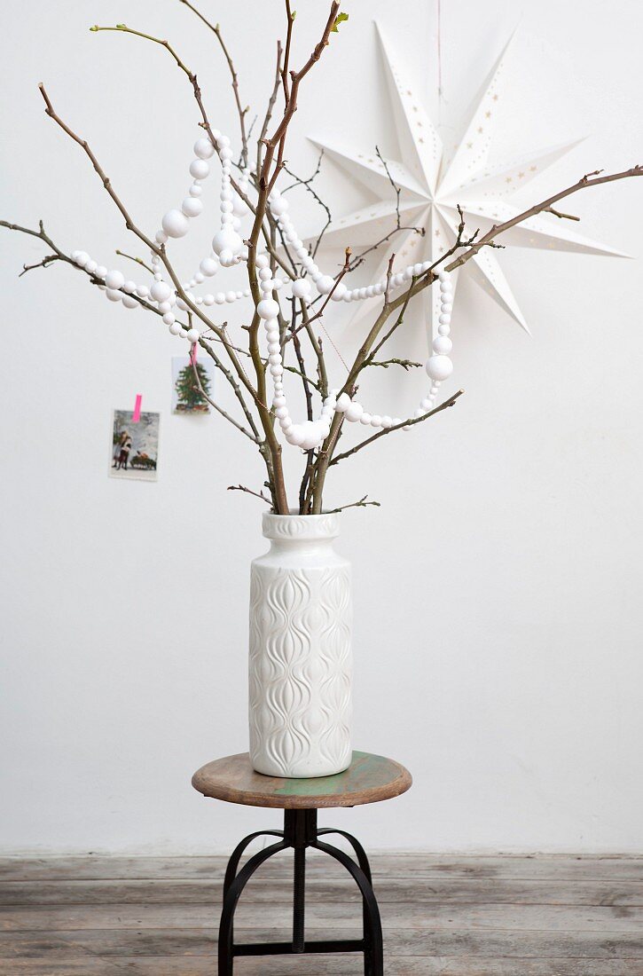 Garland made from white paper balls hung from branches in white vase