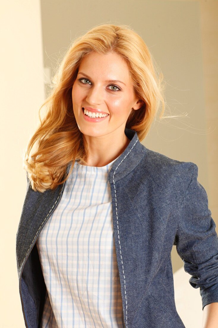 A blonde woman wearing a checked short-sleeved top and a denim jacket