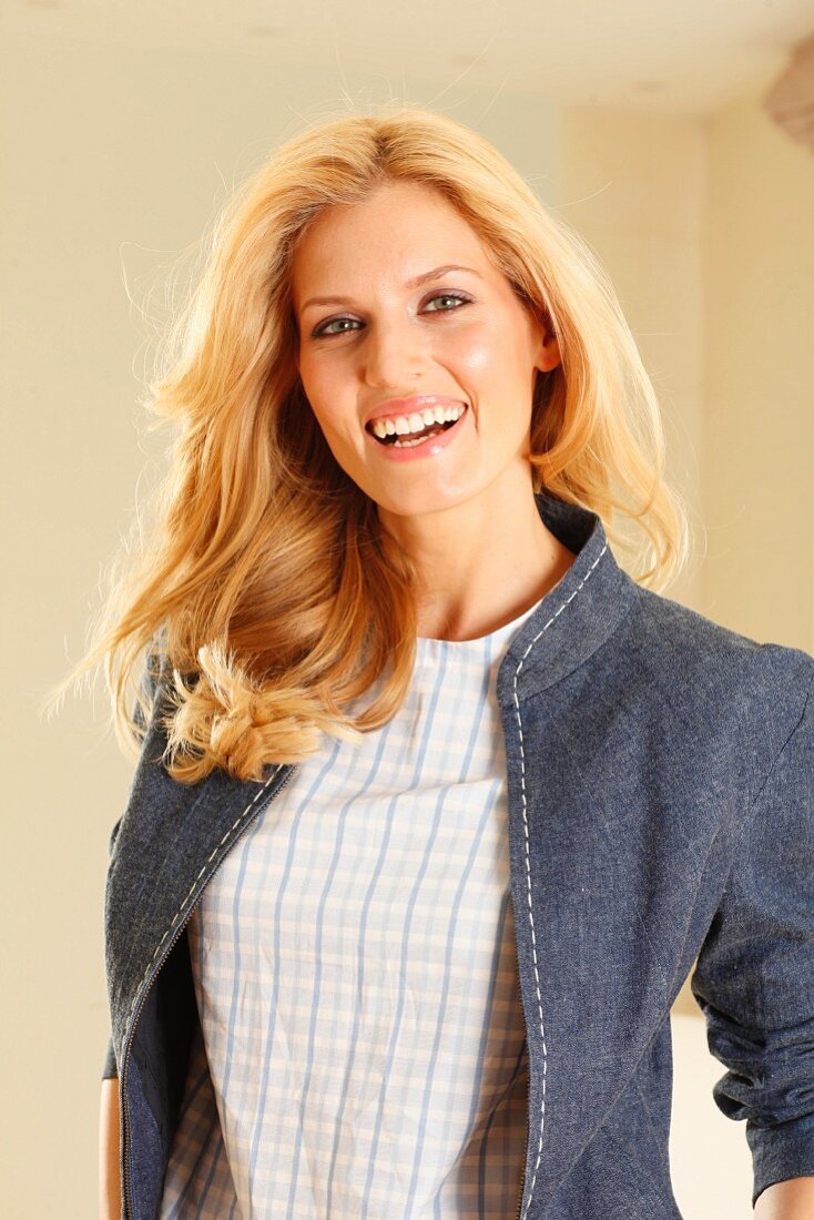 A blonde woman wearing a checked short-sleeved top and a denim jacket