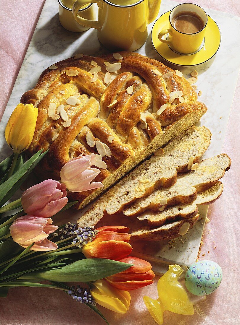 Yeast plait with almonds for Easter; tulips, coffee, Easter egg
