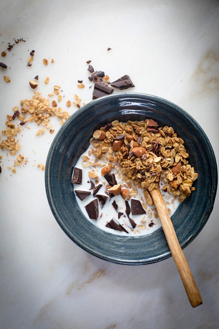 Peanut butter granola with cocoa nibs and chopped almonds and dark chocolate with milk on a marble table