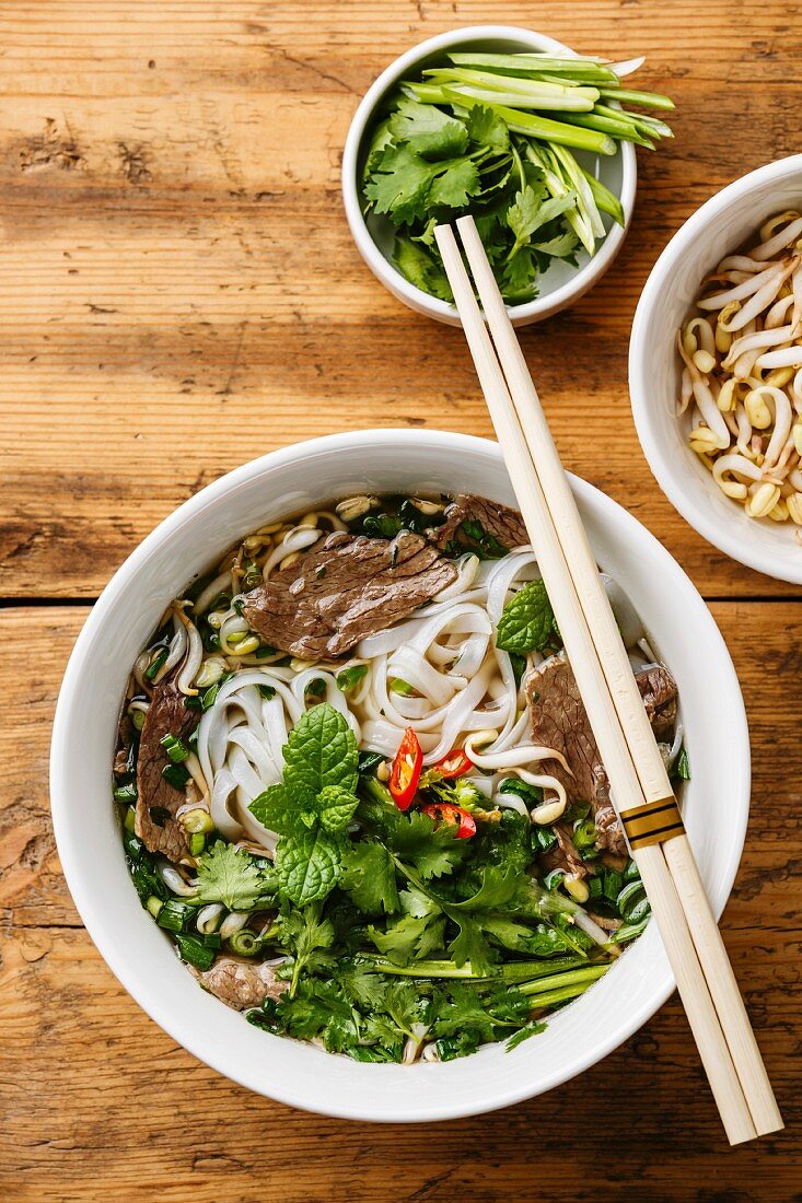 Pho Bo vietnamese Soup with beef and soybean seedlings on wooden background