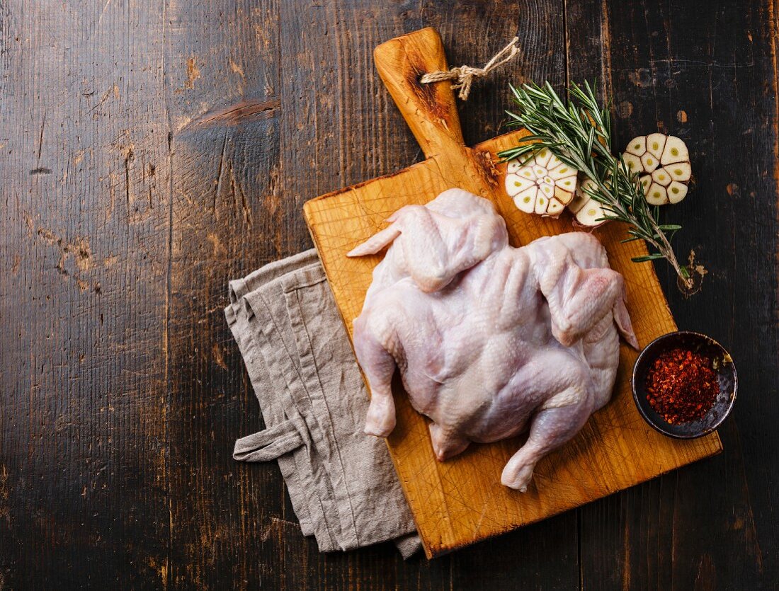 Raw whole chicken on wooden background