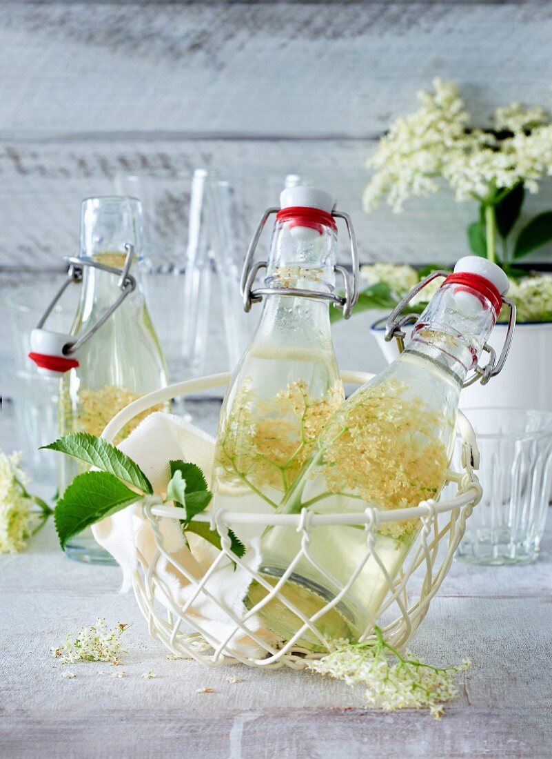 Elderflower syrup in small bottles in a wire basket