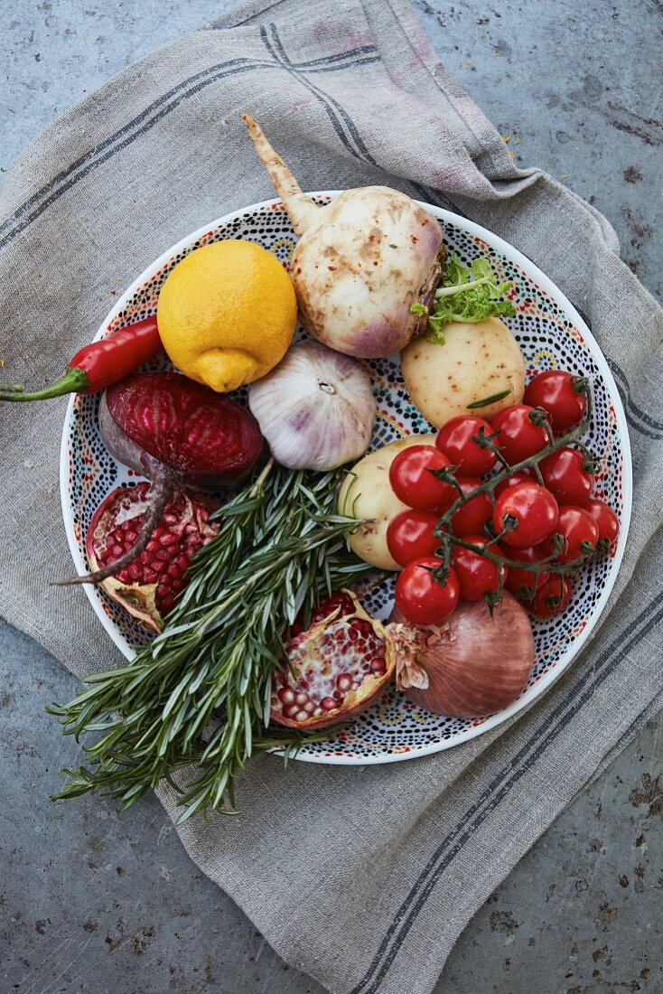 Fresh vegetables, fruits and herbs on a plate (top view)