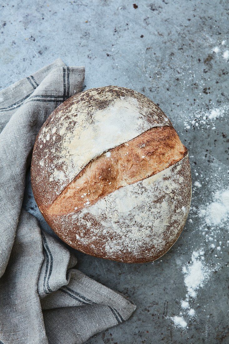 Ein Laib Brot mit Leinentuch auf Steinuntergrund (Aufsicht)