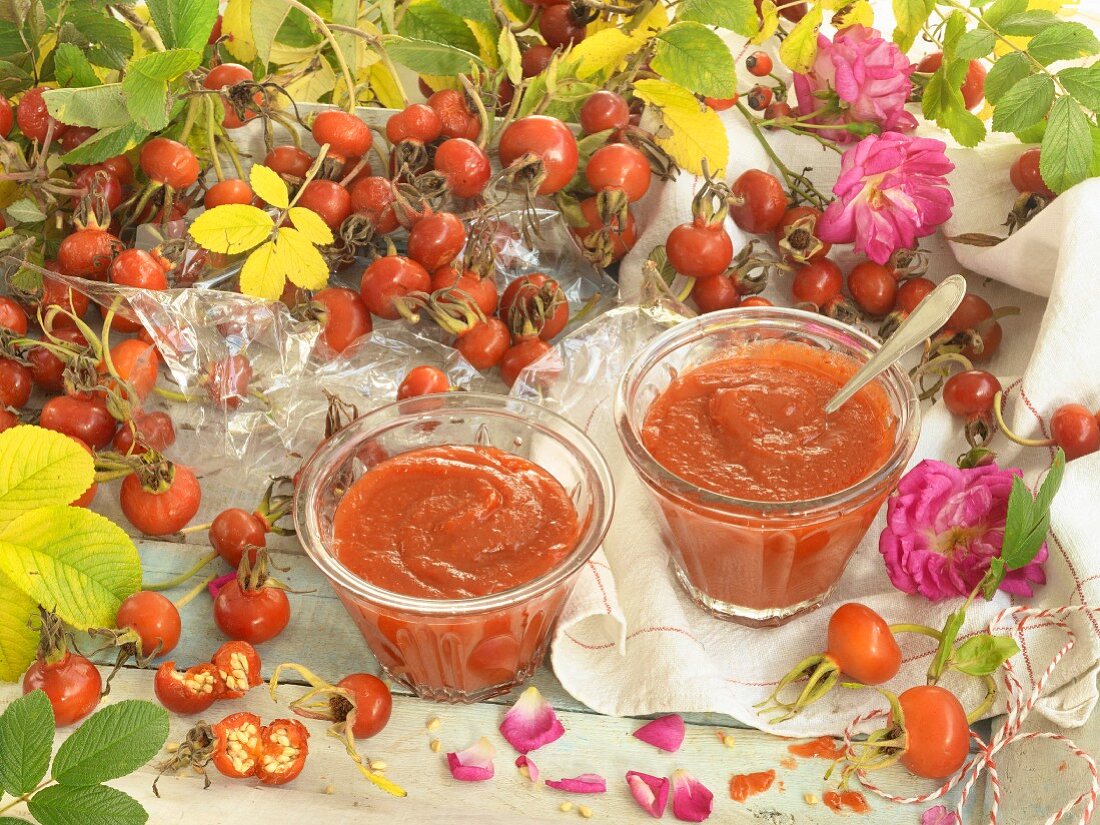 Two glasses of rosehip jam surrounded by roses