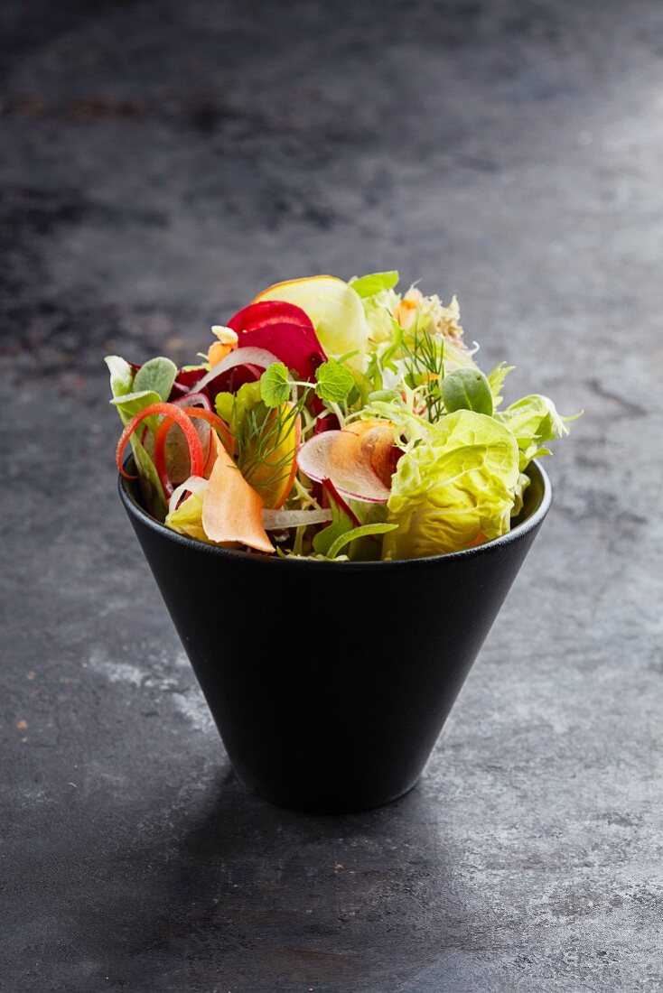 A mixed salad with vegetables and herbs in a small bowl