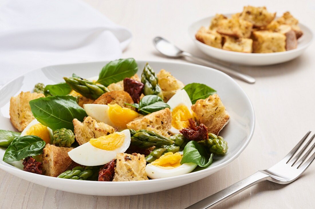 Bread salad with green asparagus, dried tomato, eggs and basil