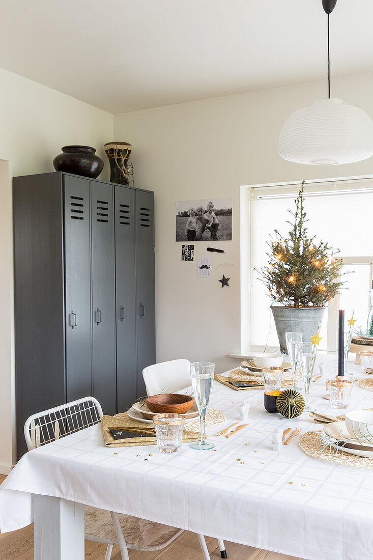 Grauer Spind hinter weihnachtlich gedecktem Esstisch in Weiß