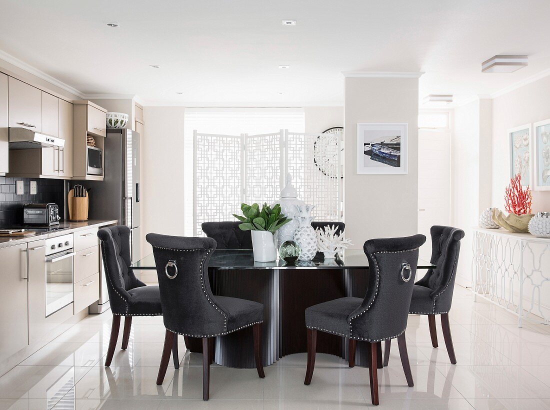 Elegant velvet-covered chairs around designer table in bright kitchen