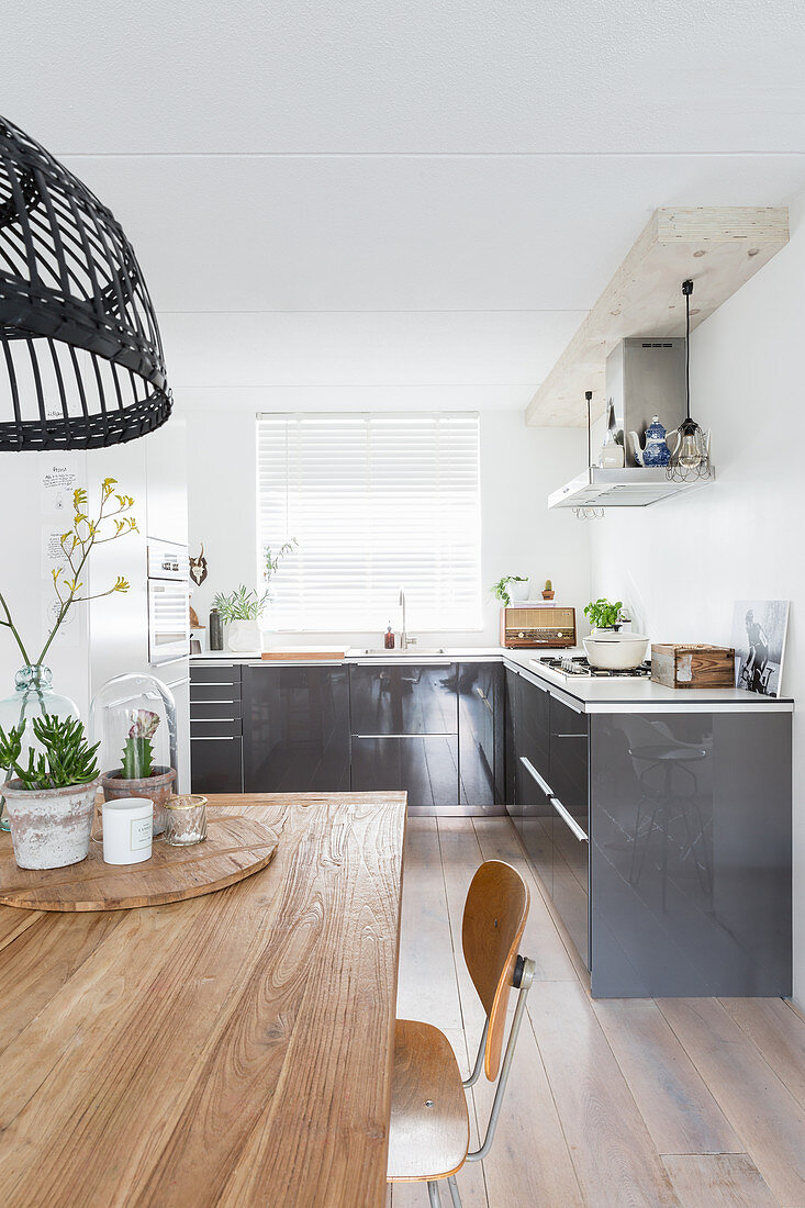 View across wooden dining table into modern open-plan kitchen