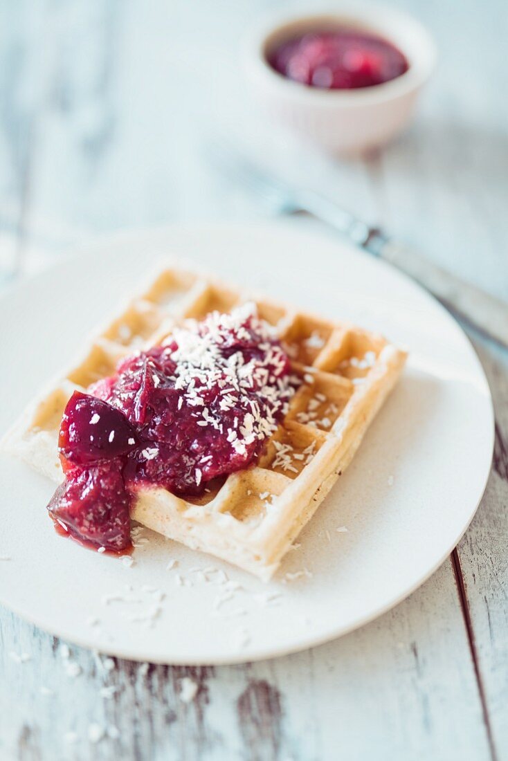 A Belgian waffle with plum compote and coconut chips