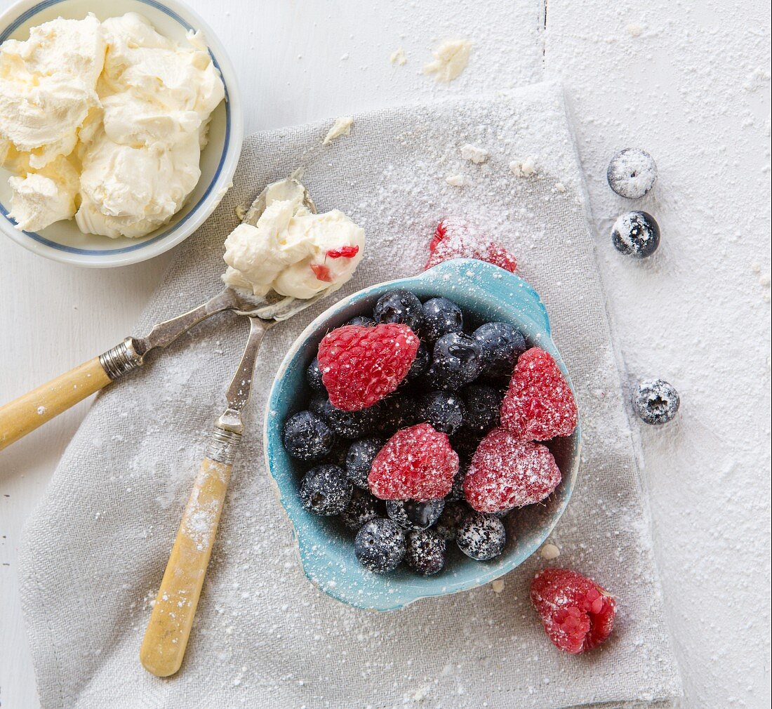 Himbeeren und Heidelbeeren in Schüssel mit Schlagsahne