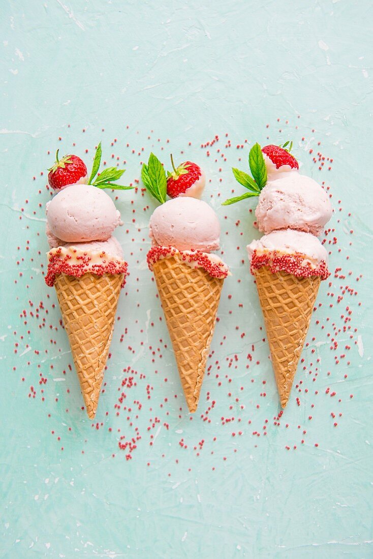 Strawberry ice cream in ice cream cones with sprinkles