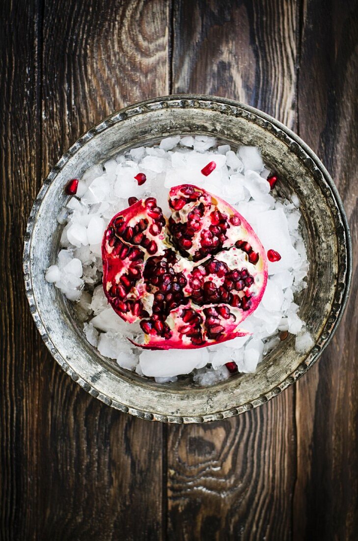 Pomegrante on ice with a dark wooden background