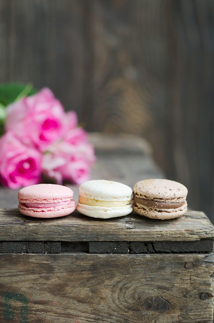 Schokoladen-, Erdbeer- und Vanillemacarons auf Holzkiste