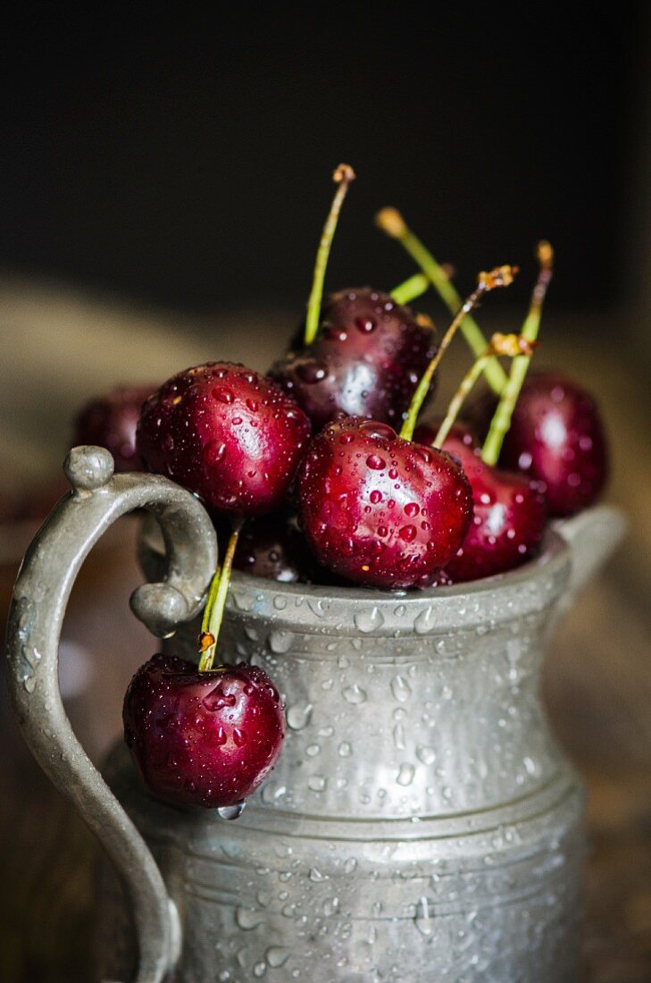 Freshly washed red summer cherries in a pewter jug