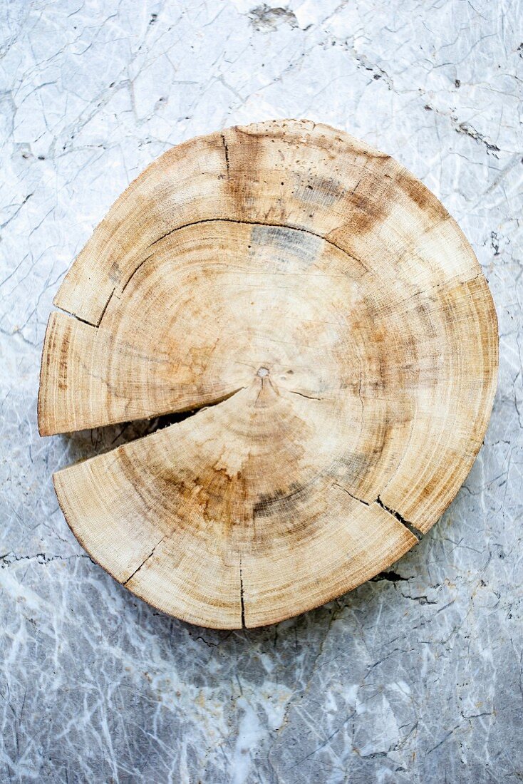 Eine Holzscheibe mit Spalt auf einer gemaserten Steinplatte