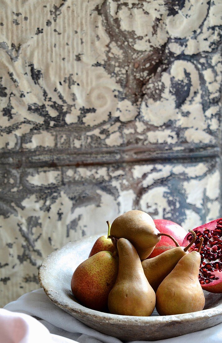 Birnen und Granatapfel in Steinschale