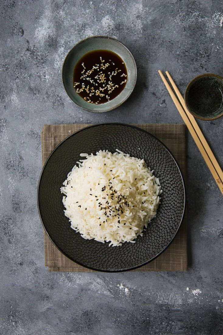 Boiled basmati rice with sesame seeds on a black plate (Asia)