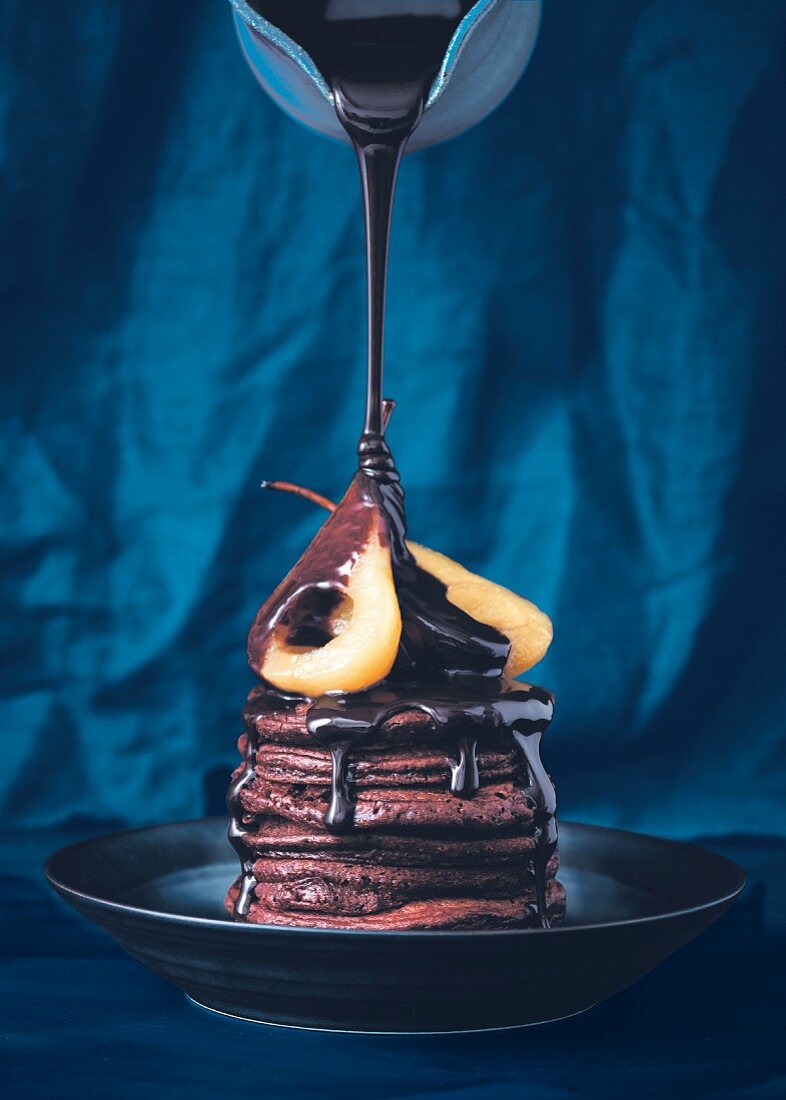 Schokoladensauce wird über Schokoladen-Pancakes mit pochierten Birnen gegossen