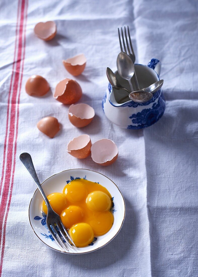 Egg yolks on a plate next to broken eggshells
