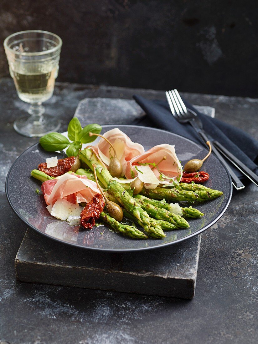 Grilled asparagus with sheep's cheese, prosciutto and capers