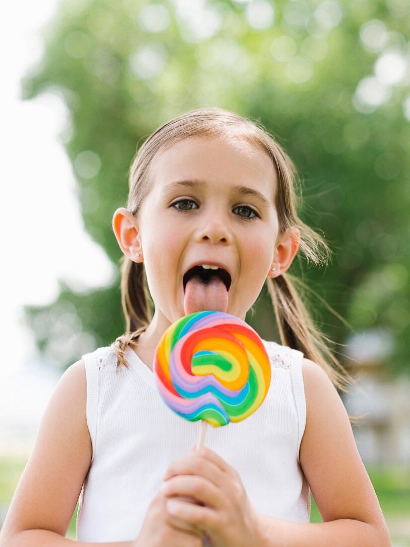 Mädchen schleckt an buntem Lolli