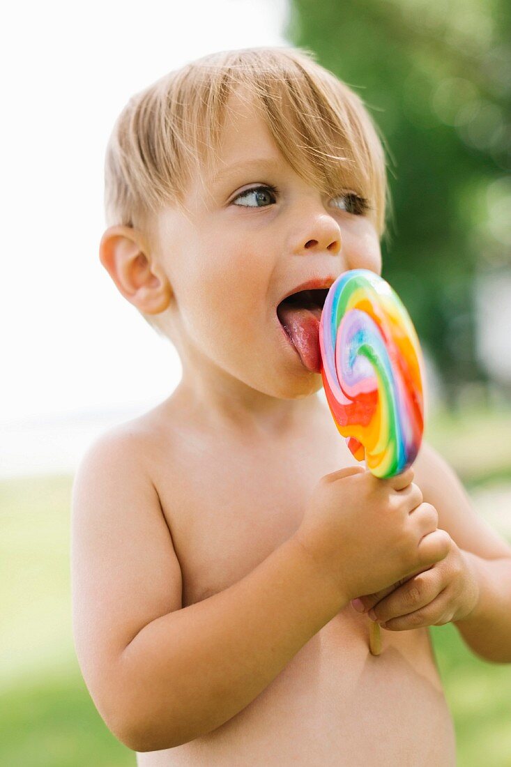 Junge schleckt an einem bunten Lolli