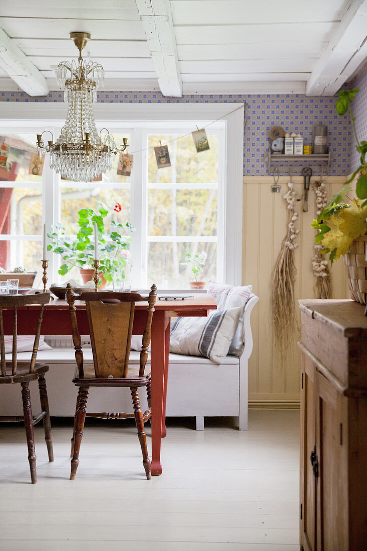 Alte Stühle am roten Tisch in skandinavischer Landhausküche