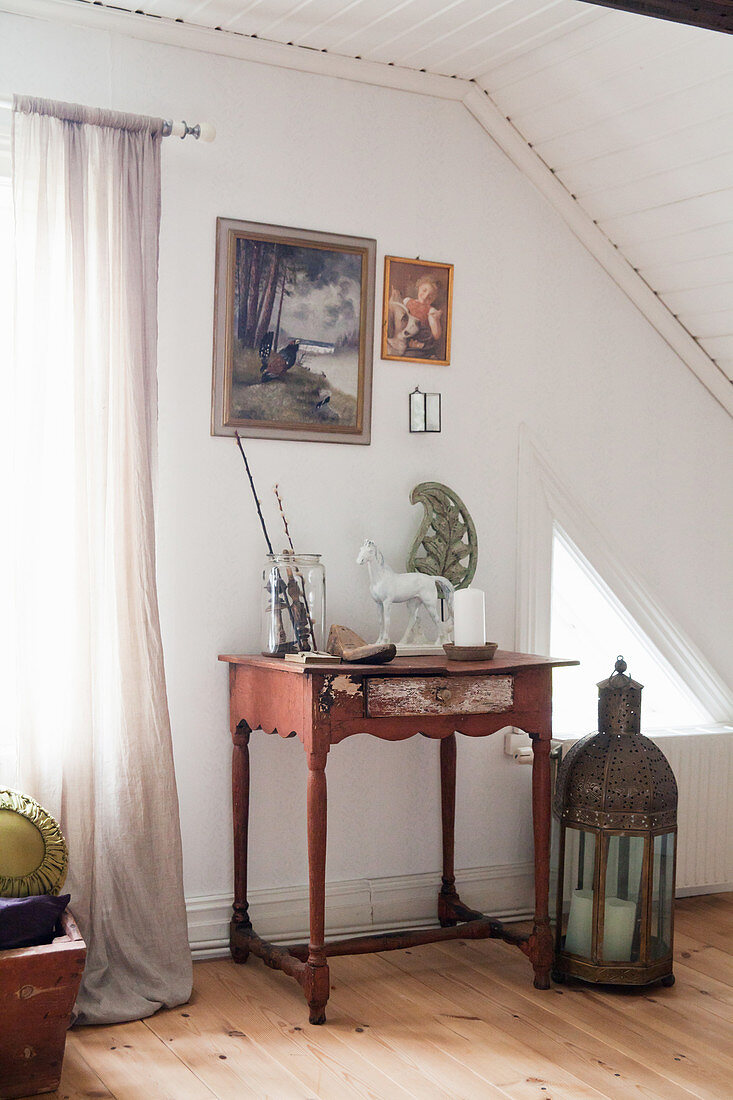 Large lantern on floor next to small red table with vintage accessories