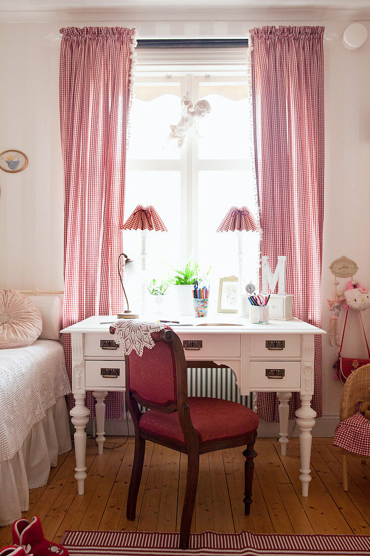 Roter Polsterstuhl und antiker Schreibtisch am Fenster im Kinderzimmer