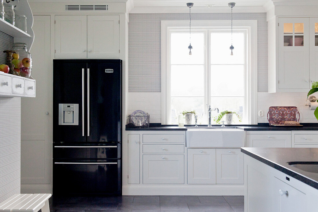 Black fridge in white country-house kitchen with panelled cabinets
