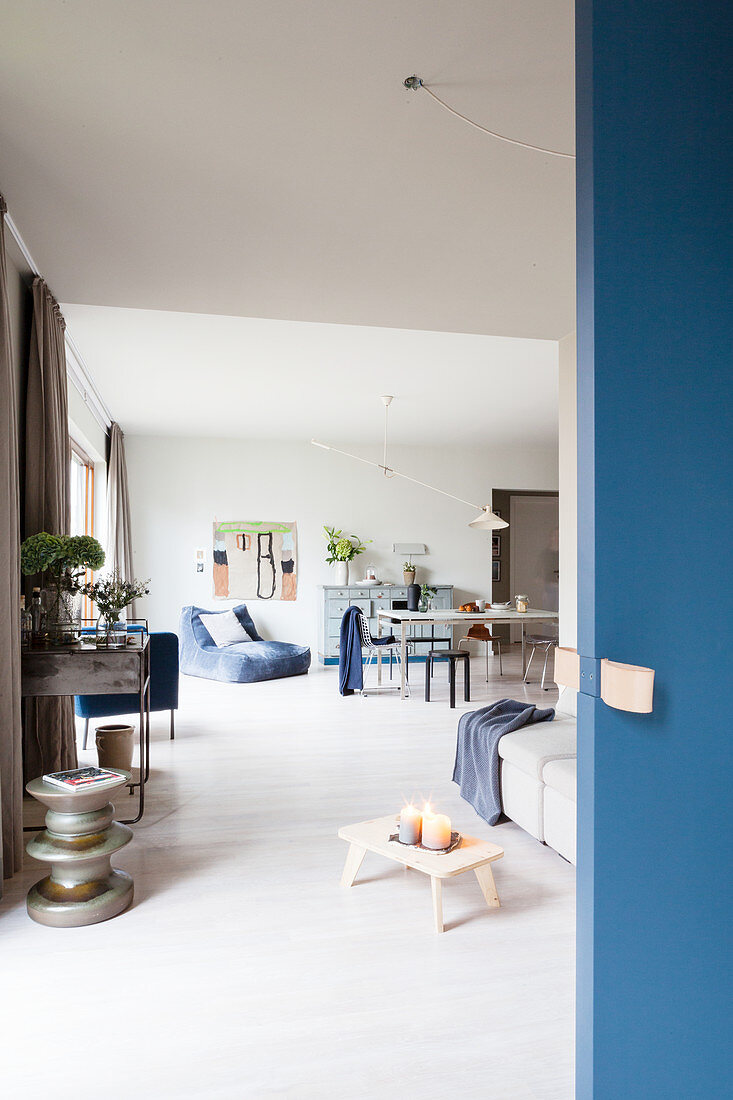 Blaue Schiebetür zum offenen Wohnraum mit Sofa und Esstisch