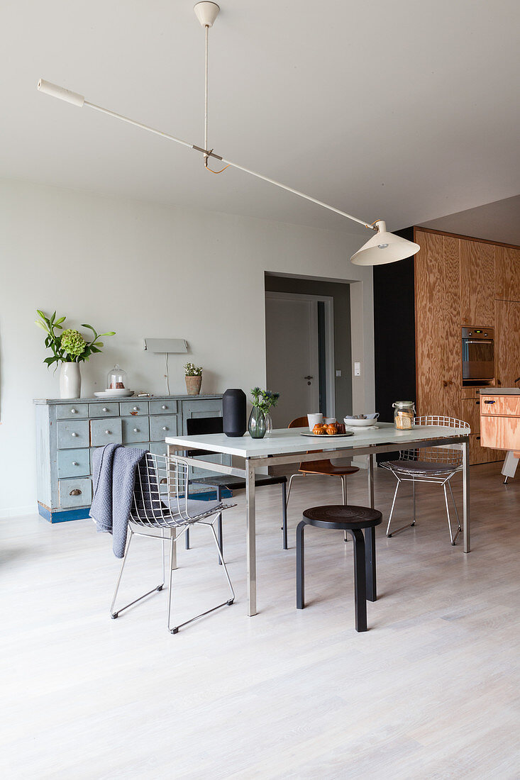 Various chairs around dining table in front of plywood kitchen