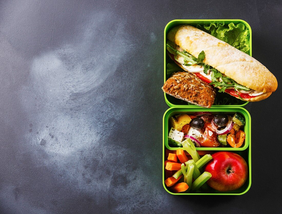Take out food Lunch box with Tuna and egg Sandwich, Greek salad and vegetables on blackboard background