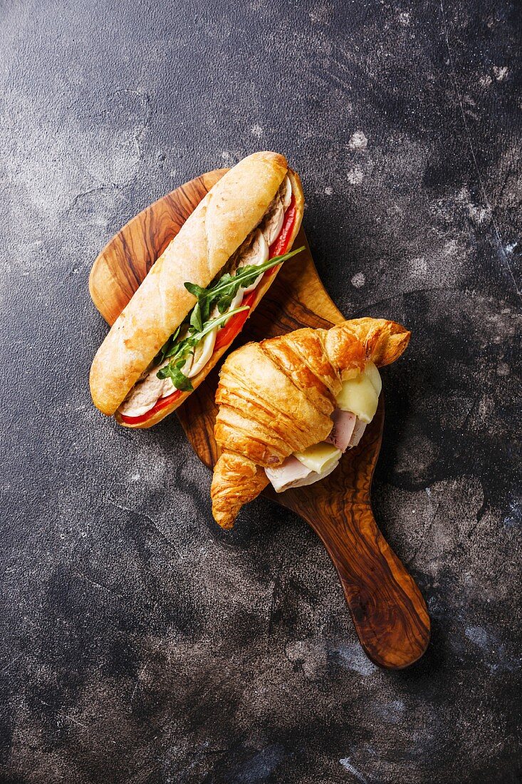Thunfisch-Sandwich mit Ei und Croissant mit Käse und Schinken auf Holzbrett
