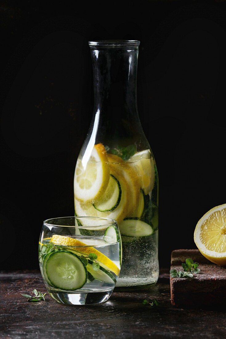 Citrus cucumber sassy sassi water for detox in glass bottle on dark black background
