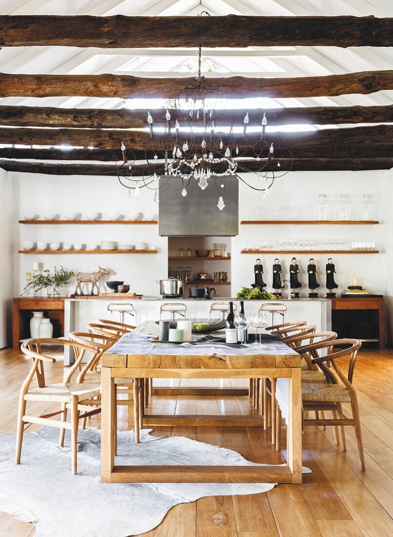 Classic chairs and rustic wooden beams in dining area in front of open-plan kitchen