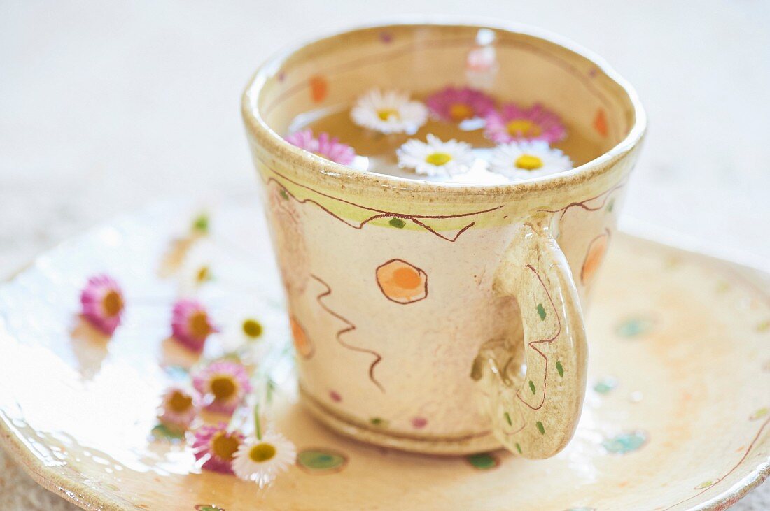 Tee mit Gänseblümchen in Keramiktasse