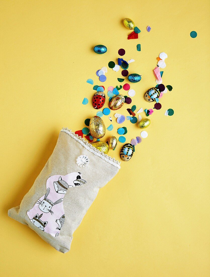Confetti and sweets fall out of cloth bags with an Easter bunny