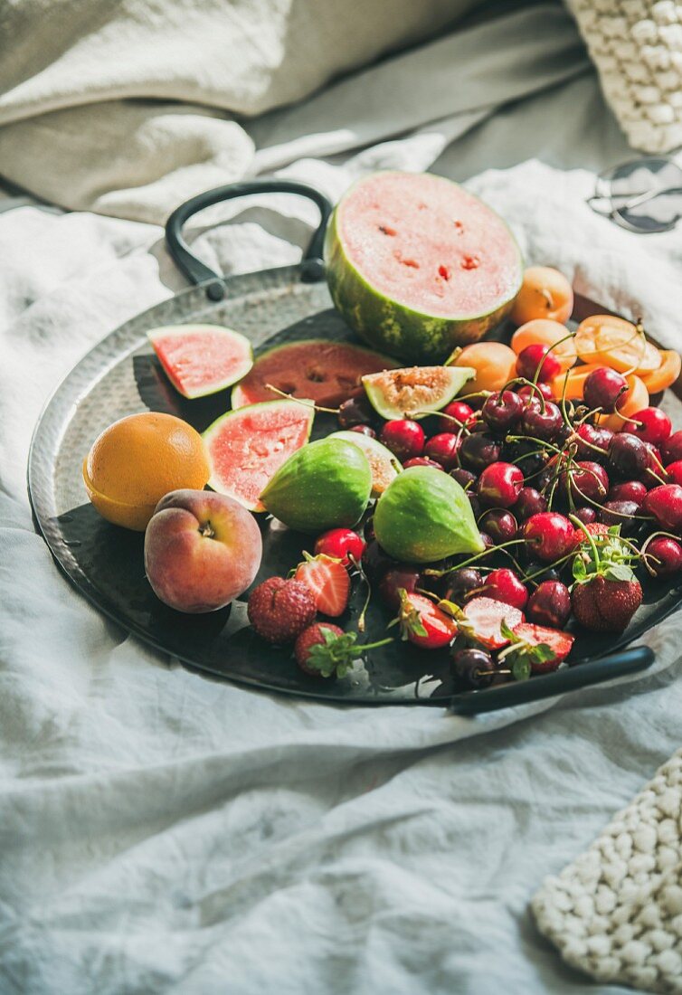 Tray full of fresh seasonal fruit over light blanket background