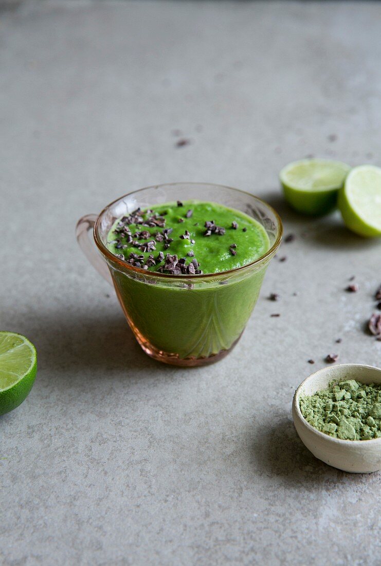 Healthy green vegetable and matcha smoothie drink with cocoa nibs
