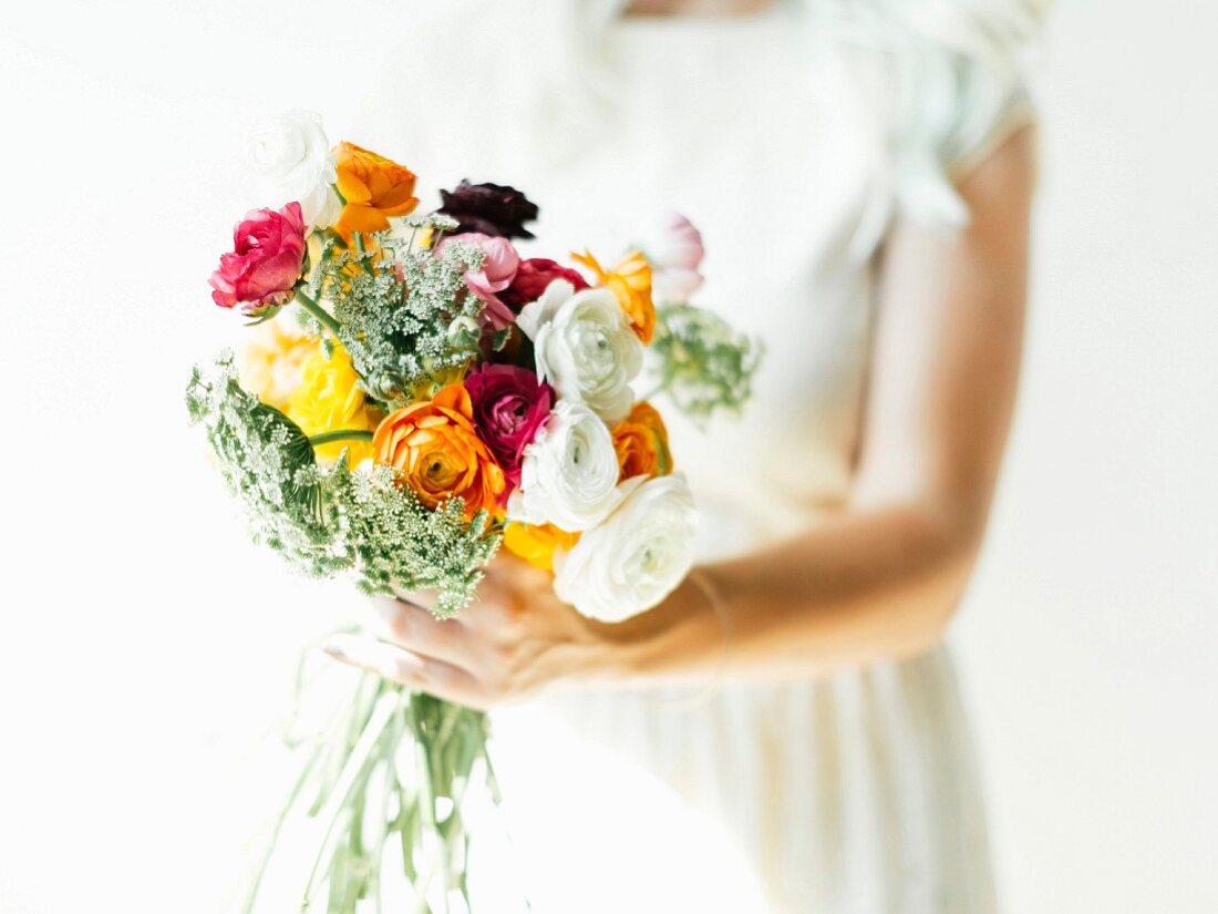 Woman holding bouquet of colourful ranunculus and cow parsley