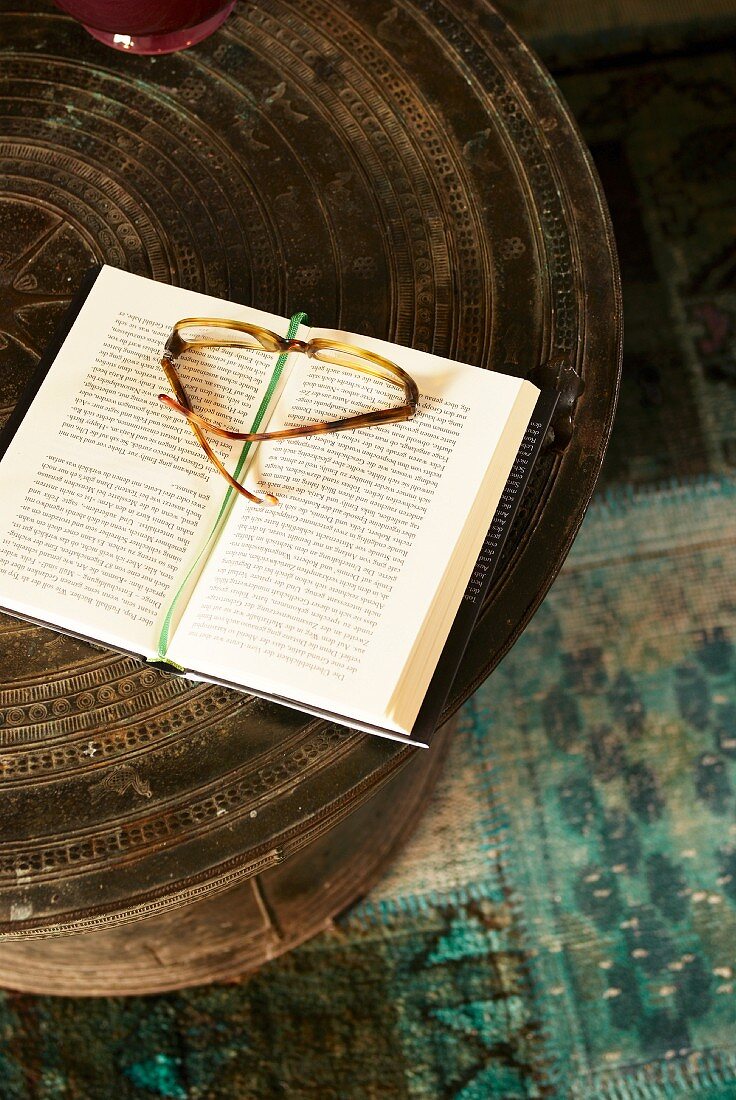 Reading glasses on book on ethnic table