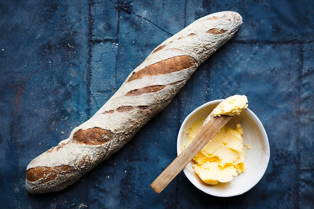 A baguette and a bowl of butter (top view)