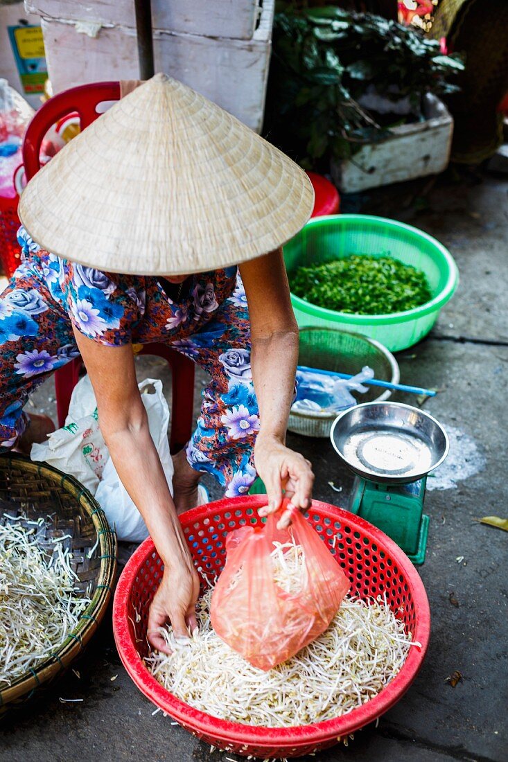 A woman selling bean sprouts at a market in Hoi An, Vietnam