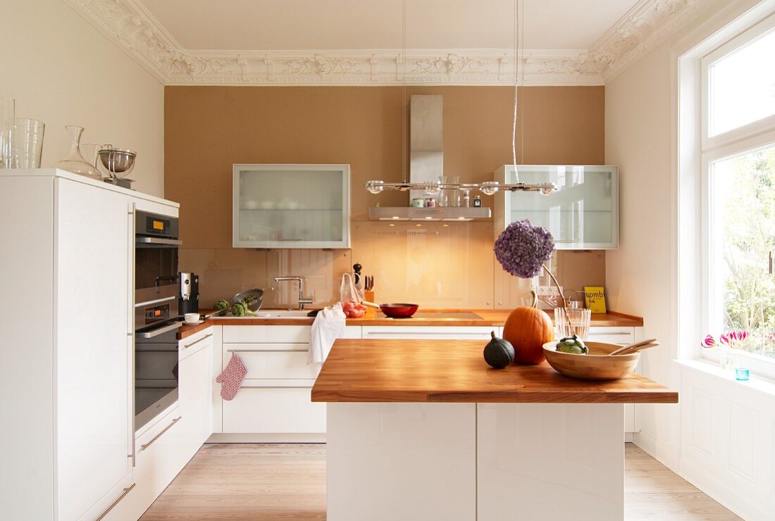 Elegant white kitchen with painted accent wall and stucco frieze