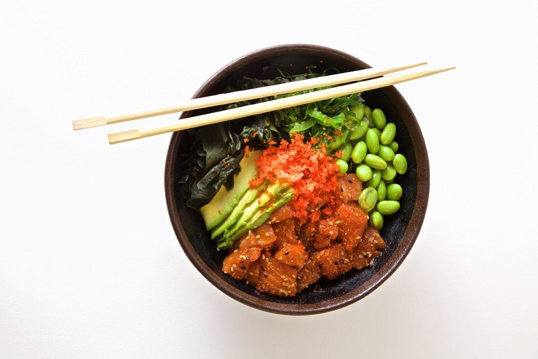 Poke bowl with salmon, edamame, seaweed and sesame oil (seen from above)